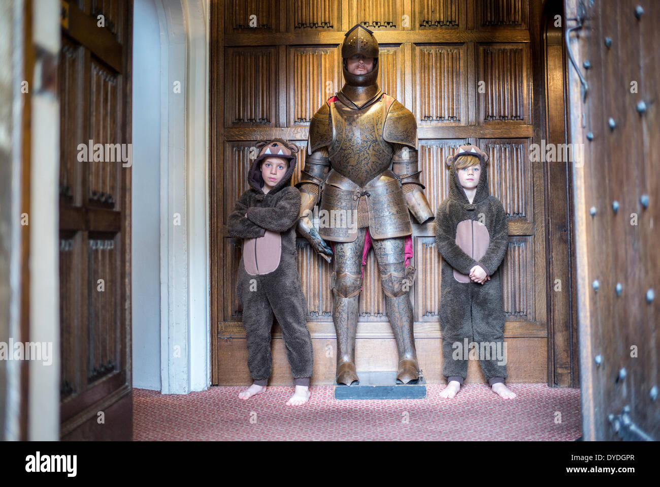 Deux garçons en onesies debout à côté d'un chevalier en armure à Thornbury Castle. Banque D'Images