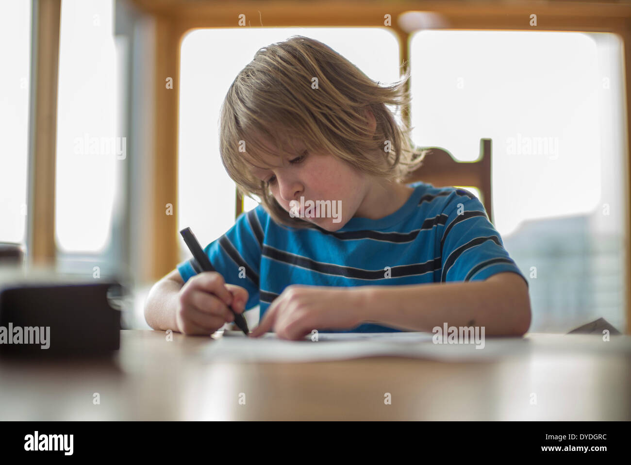 Un garçon de sept ans à la table de dessin. Banque D'Images