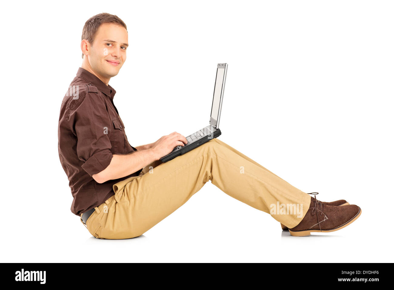 Guy working on laptop assis sur le plancher Banque D'Images