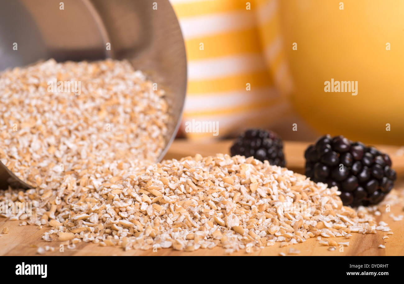 Coupe de l'acier de l'avoine s'échappant d'une tasse à mesurer avec des mûres fraîches Banque D'Images