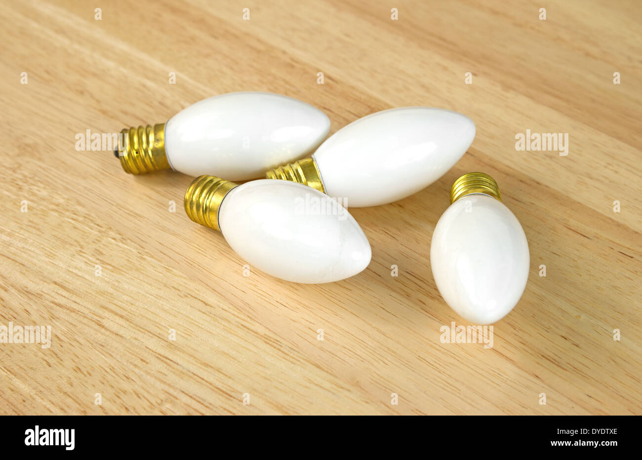 Quatre petites ampoules vanity blanc sur une table à grain de bois. Banque D'Images