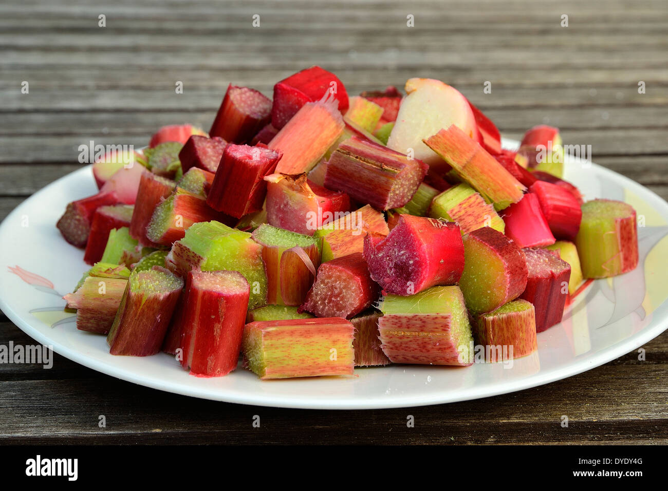 Assiette de morceaux de rhubarbe couper sur une table de jardin. Banque D'Images
