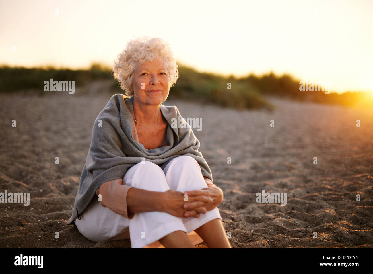 Portrait of happy vieille femme assis sur la plage. Dame de race blanche à la retraite de détente en plein air Banque D'Images