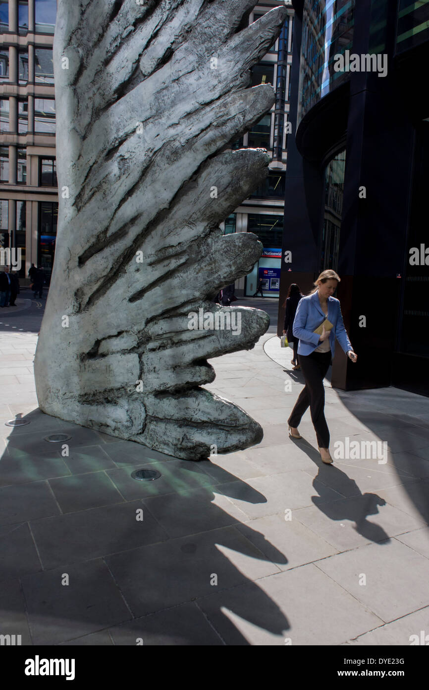 Les travailleurs de la ville par le passage de l'oeuvre d'un géant de l'aile de bronze lors d'un midi de printemps dans le quartier financier de Londres. Comme la lumière se reflète sur les immeubles de bureaux à proximité, la foule à l'heure du déjeuner devant ce géant des illustrations sur leur façon de réunions et sandwicheries. Les dix mètres de haut est la sculpture en bronze par le président de la Royal Academy of Arts, Christopher Le Brun, commandé par Hammerson en 2009. Elle est appelée 'La Ville' de l'aile et a été jeté par Morris Singer, fondateurs de l'art réputé pour être la plus ancienne fonderie d'art dans le monde. Banque D'Images
