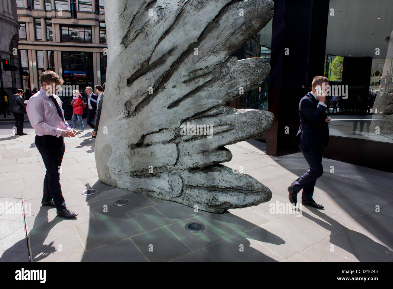 Les travailleurs de la ville par le passage de l'oeuvre d'un géant de l'aile de bronze lors d'un midi de printemps dans le quartier financier de Londres. Comme la lumière se reflète sur les immeubles de bureaux à proximité, la foule à l'heure du déjeuner devant ce géant des illustrations sur leur façon de réunions et sandwicheries. Les dix mètres de haut est la sculpture en bronze par le président de la Royal Academy of Arts, Christopher Le Brun, commandé par Hammerson en 2009. Elle est appelée 'La Ville' de l'aile et a été jeté par Morris Singer, fondateurs de l'art réputé pour être la plus ancienne fonderie d'art dans le monde. Banque D'Images