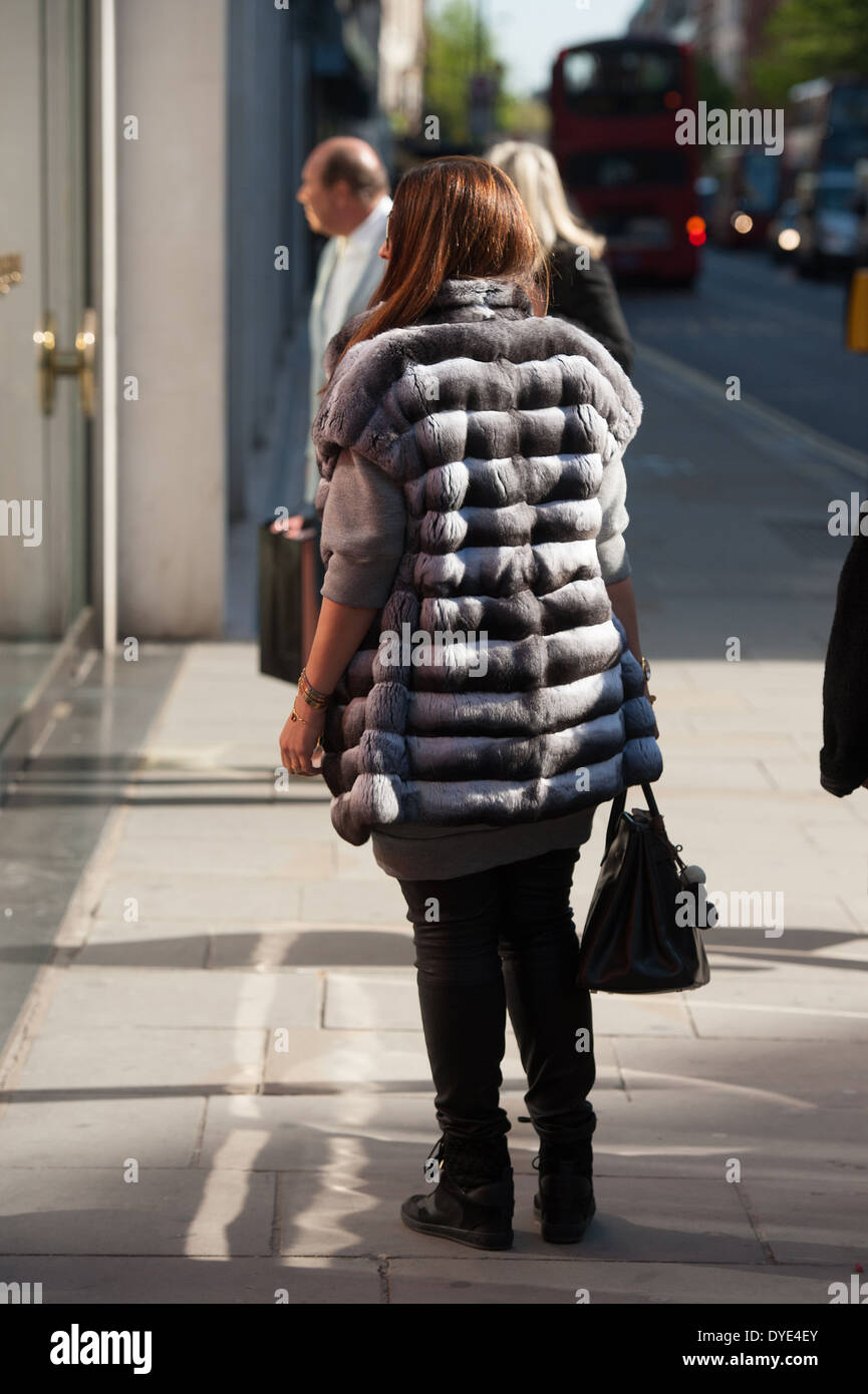 Une femme marche dernières boutiques windows habillé en manteau de fourrure  chinchilla coûteux Photo Stock - Alamy