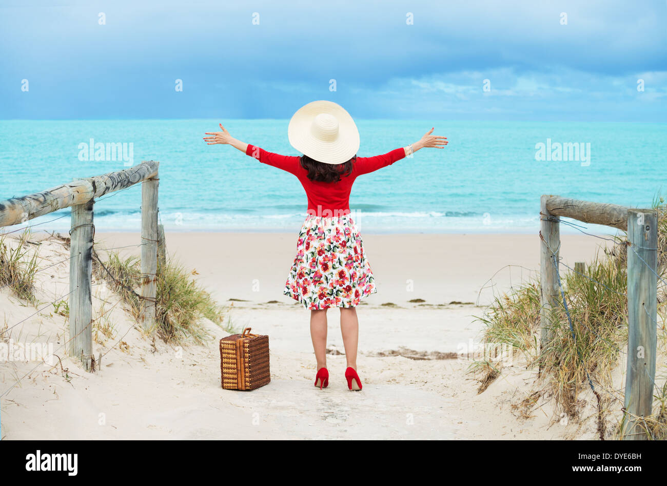 Belle femme en robe de style rétro voyageur sur la plage Banque D'Images