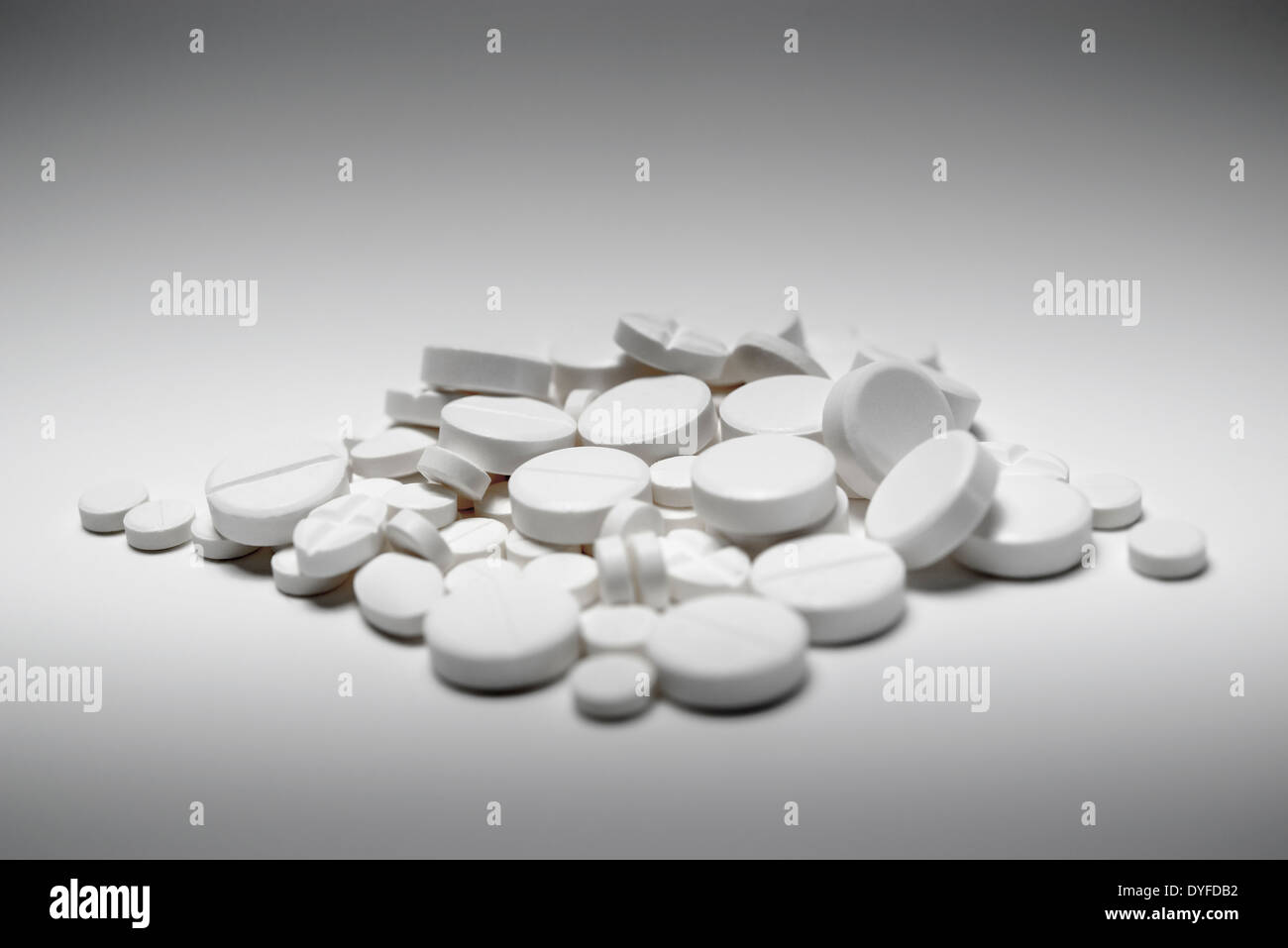 Un peu au hasard tas de pilules blanches mélangées de différentes tailles et formes, abattu en blanc. L'abus de drogues ou surdose concept. Banque D'Images