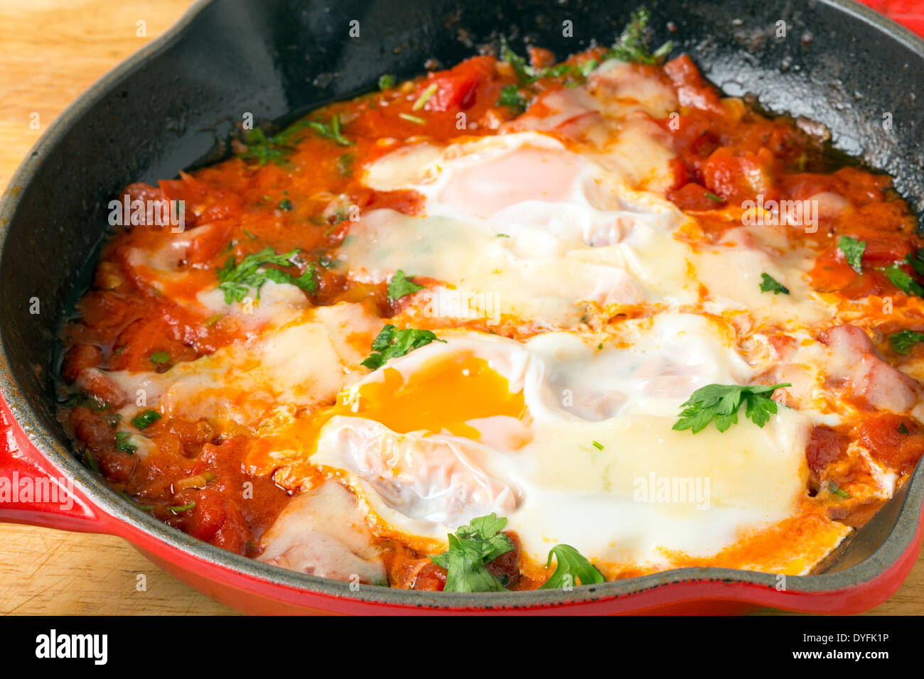 'Oeufs dans le Purgatoire', un petit-déjeuner méditerranéen plat d'œufs pochés dans une sauce tomate épicée garni de fromage fondu. Banque D'Images