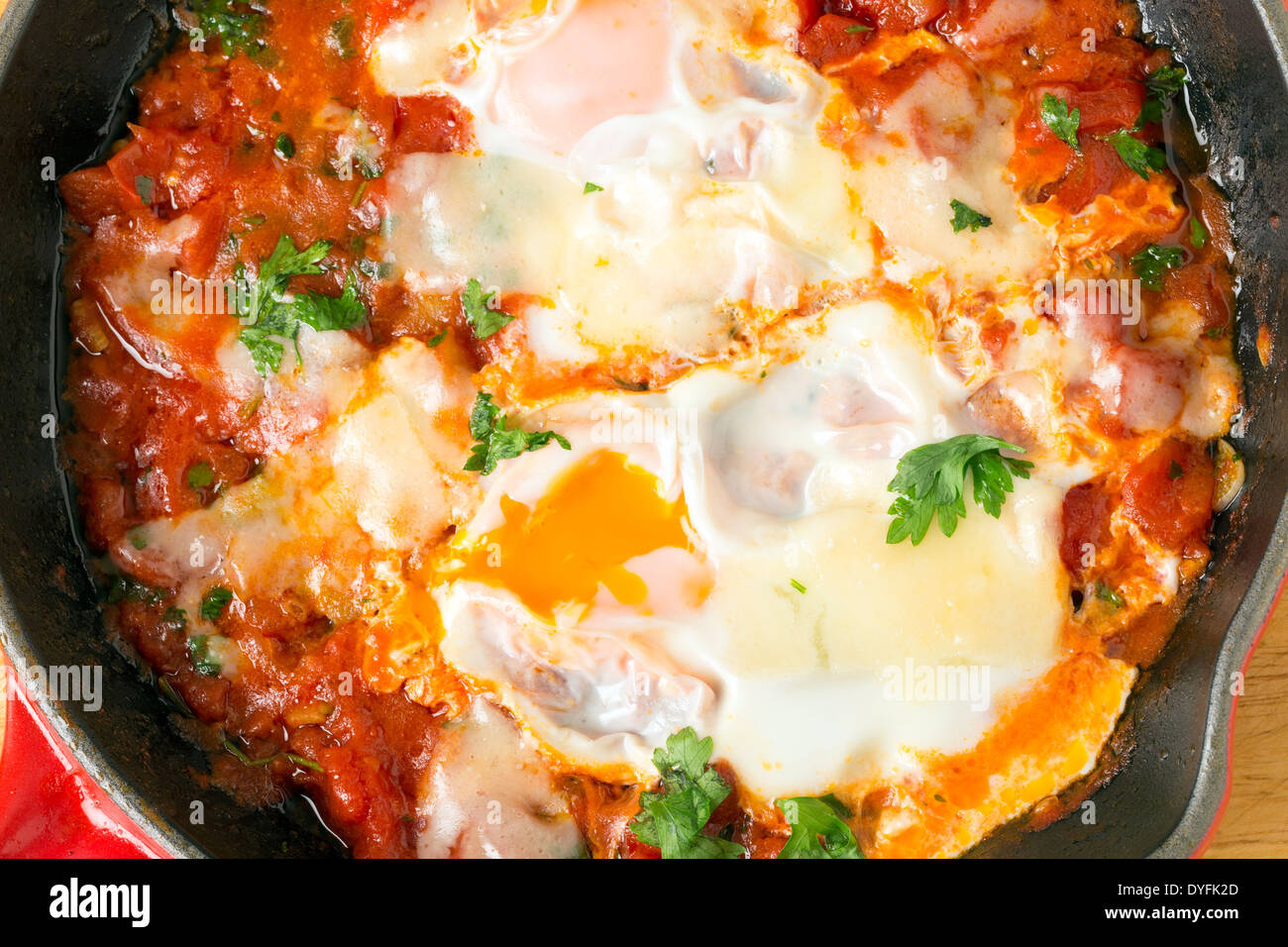 'Oeufs dans le Purgatoire', un petit-déjeuner méditerranéen plat d'œufs pochés dans une sauce tomate épicée garni de fromage fondu. Banque D'Images