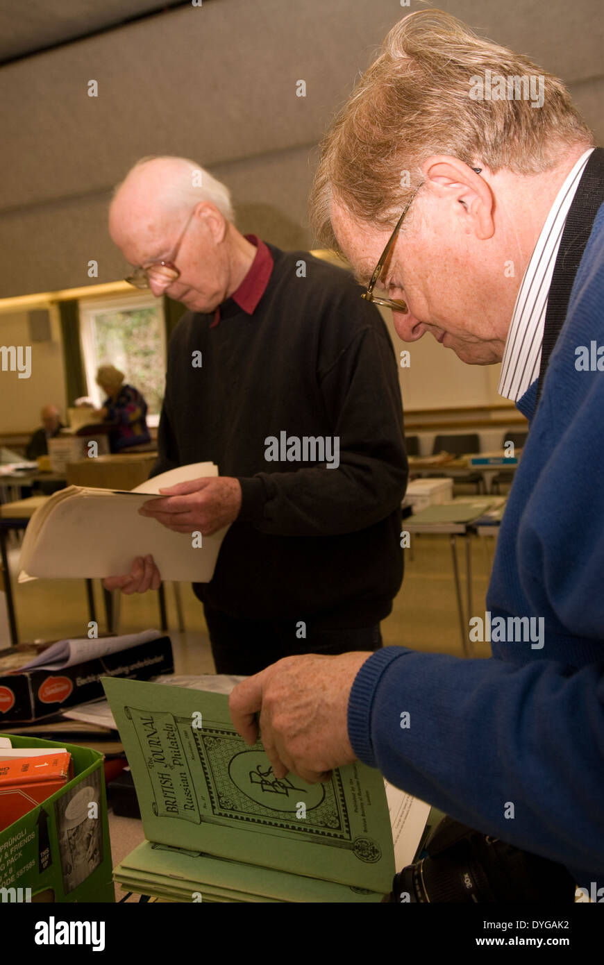 Les hommes participant à une vente aux enchères de timbres et de lire les articles destinés à la vente, Petersfield, Hampshire, Royaume-Uni. Banque D'Images