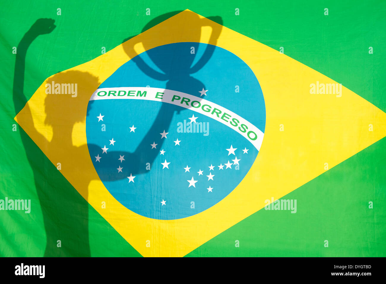 Ombre de holding trophy brésilien au soleil contre drapeau brésilien Banque D'Images