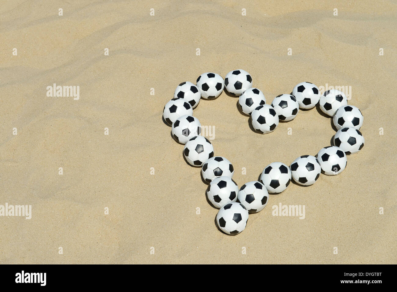 Love Football coeur fait avec des ballons de foot sur plage de sable lumineux de message à Rio de Janeiro Brésil Banque D'Images