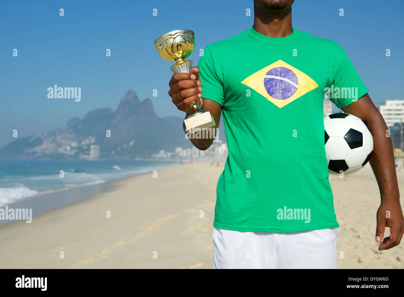 Champion Brazilian soccer player holding trophy et du football en drapeau brésilien shirt plage Ipanema Rio de Janeiro Brésil Banque D'Images