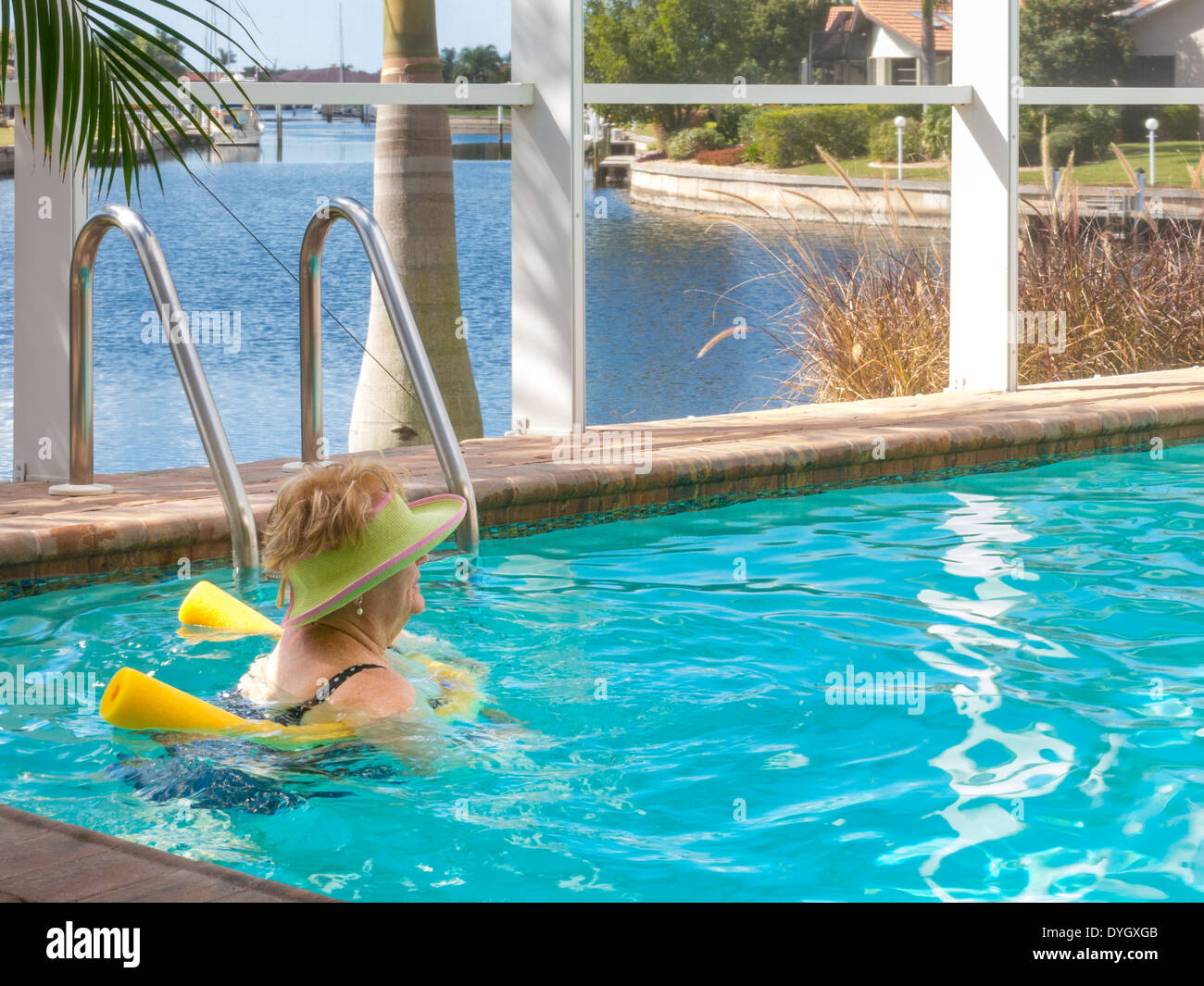 Femme mature se prélasser dans la piscine extérieure avec des nouilles, Florida, USA Banque D'Images