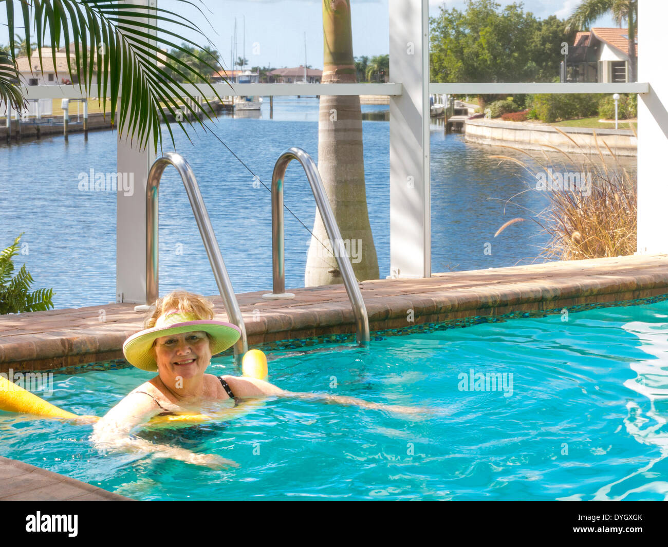 Femme mature se prélasser dans la piscine extérieure avec des nouilles, Florida, USA Banque D'Images