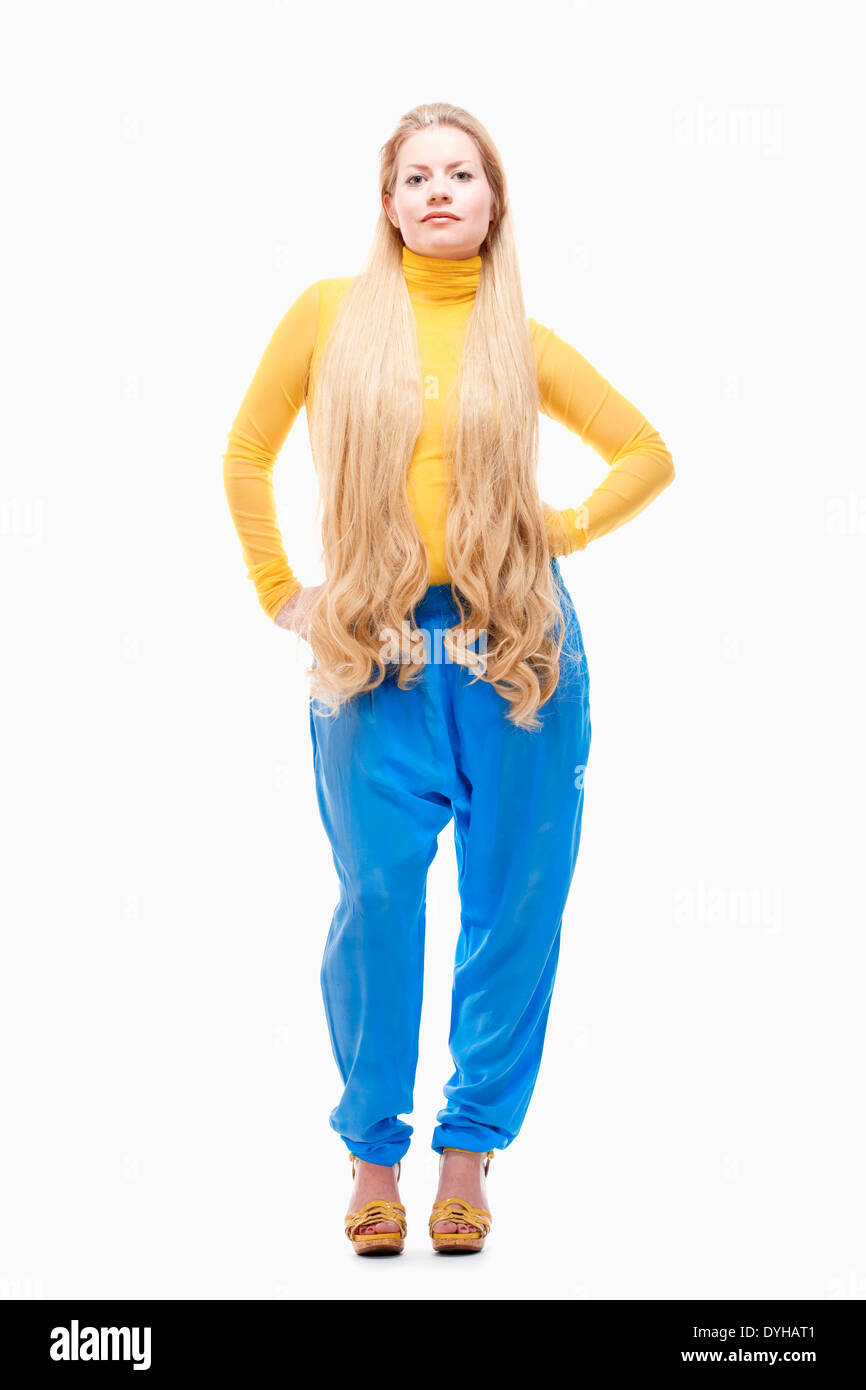 Jeune femme avec de longs cheveux blonds en jaune Top et pantalon bleu. Banque D'Images