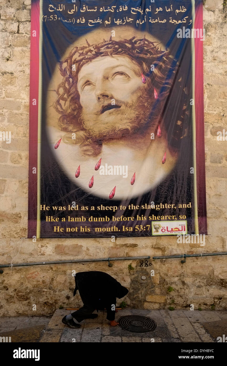 Une promenade piétonne âgées passé une grande affiche représentant Jésus le Christ sur le Patriarcat grec street dans le quartier chrétien de la vieille ville de Jérusalem Israël Banque D'Images