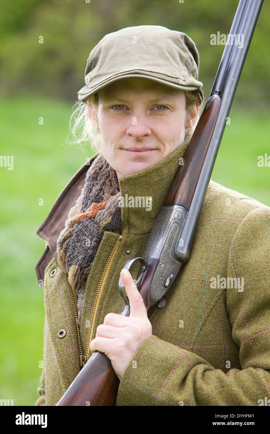 Une femme portant des vêtements de tir et à l'extérieur dans la campagne anglaise avec un fusil Banque D'Images