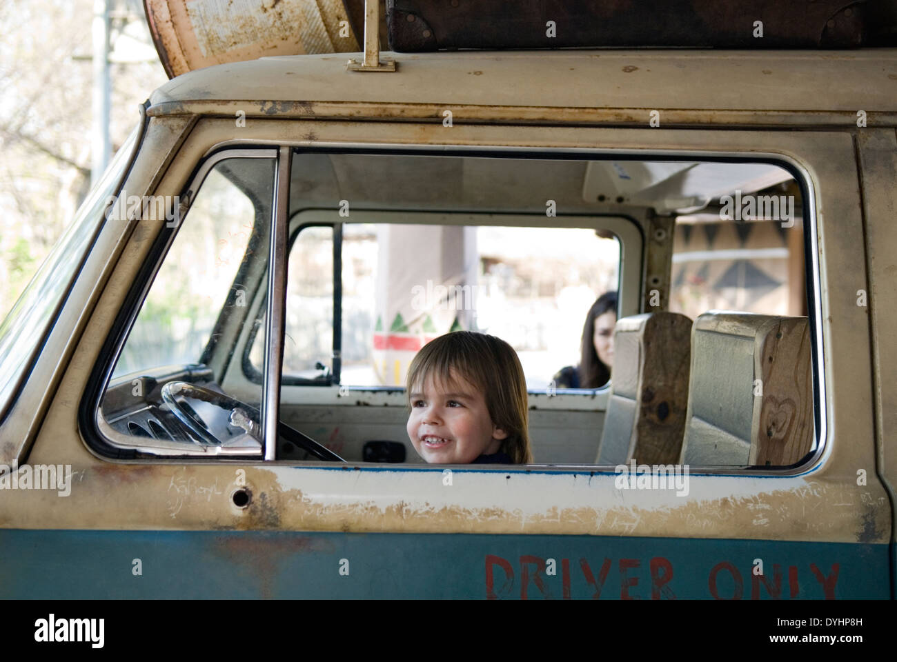 Trois ans vieux garçon assis dans un vieux van au Zoo de Louisville comme mère regarde derrière Banque D'Images