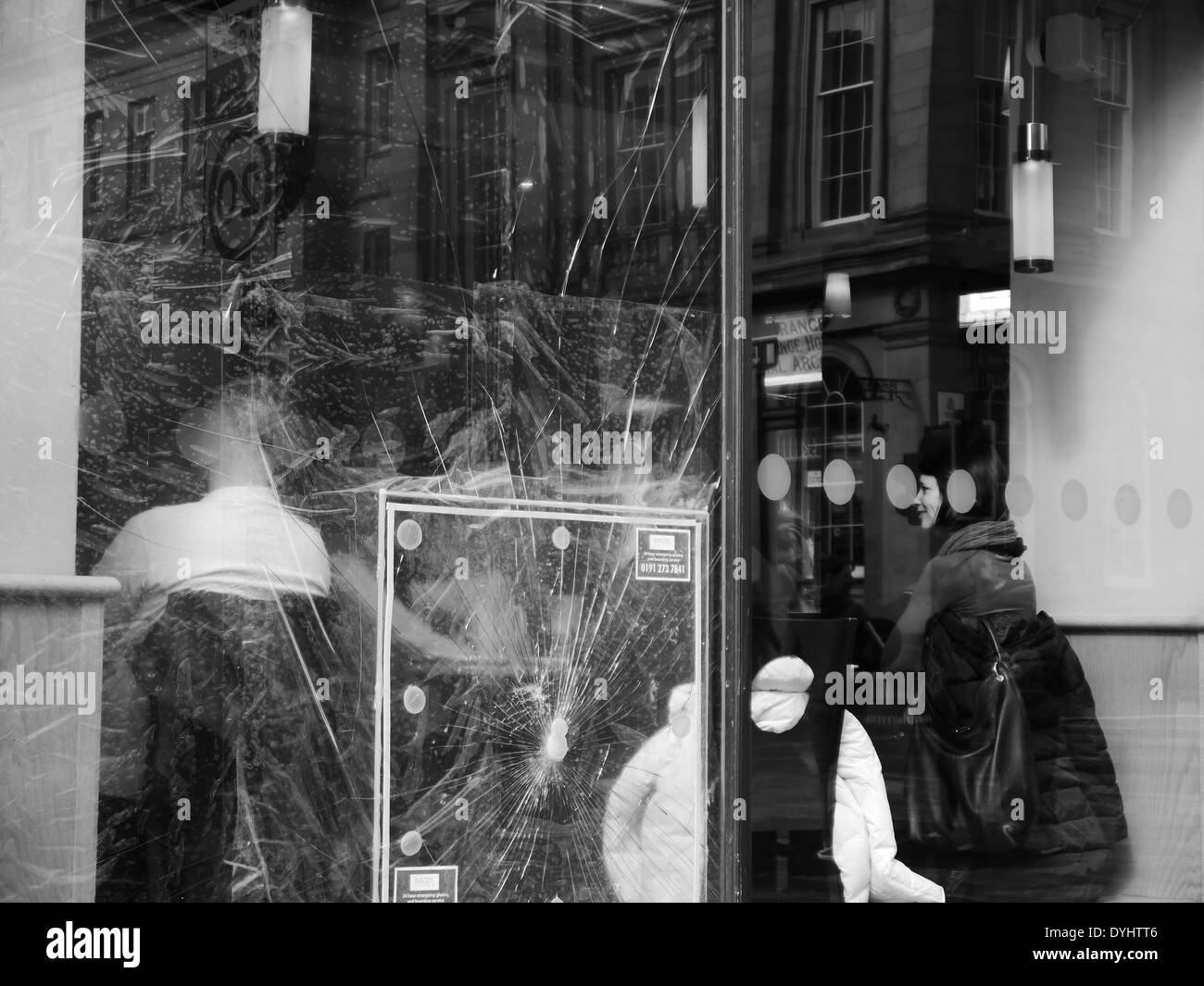 Les clients s'asseoir dans le city café derrière vandalisé, fissuré fenêtre, Newcastle upon Tyne, England, UK Banque D'Images