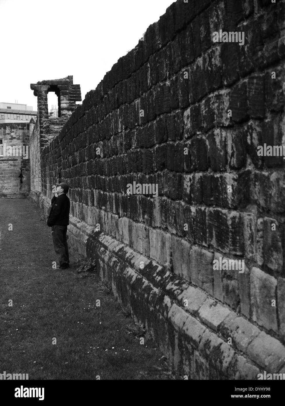 L'homme à l'aide de mobile téléphone à côté de vue partielle de la ville médiévale de mur, Newcastle upon Tyne, England, UK Banque D'Images