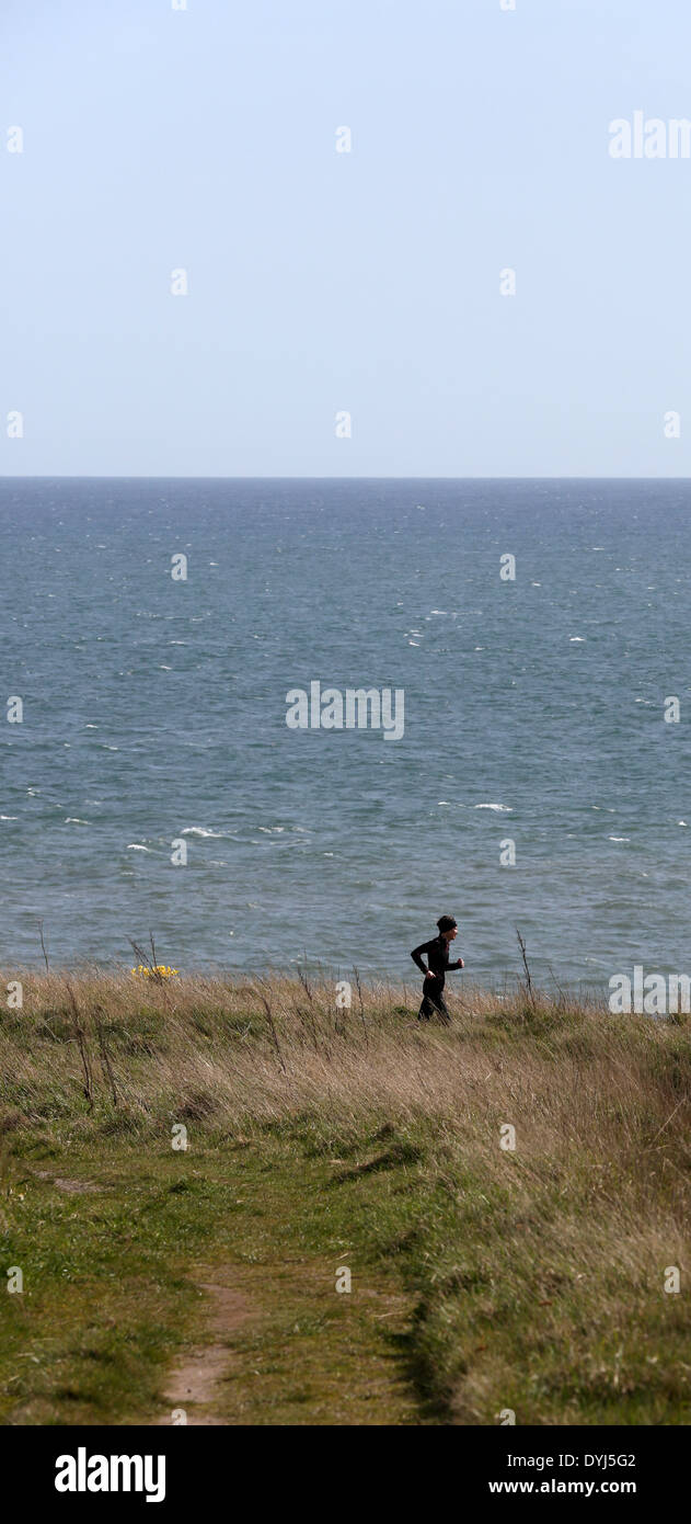 Runner sur le sentier du littoral à Cove Bay, ville d'Aberdeen, Écosse, Royaume-Uni, avec la mer du Nord à l'arrière-plan Banque D'Images