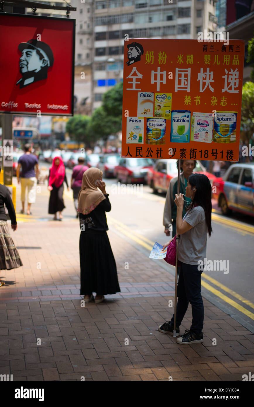 Femme tenant un signe la vente de la poudre de lait. un article populaire acheté par la Chine au cours de vacances à hong kong. Banque D'Images