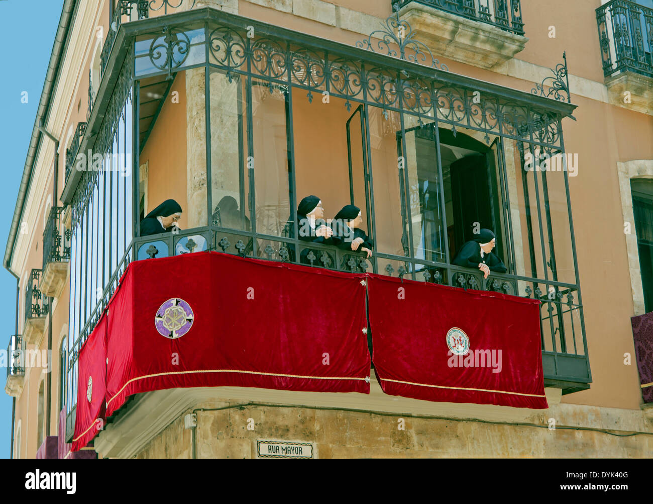 Les nonnes sur un balcon décoré de regarder le flotteur de l'Âne le dimanche des rameaux pendant la Semana Santa, Salamanca, Espagne. Banque D'Images