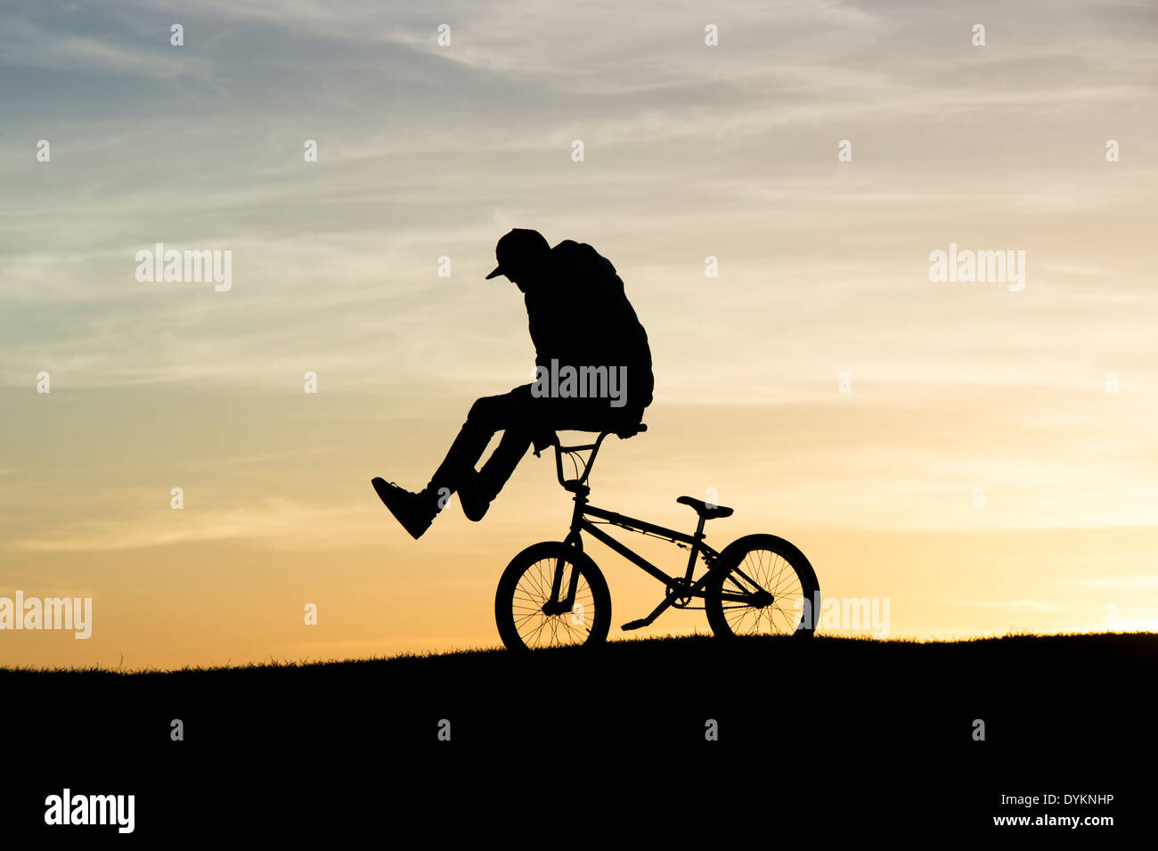 Jeune homme faisant des tours sur son vélo BMX. Silhouette Banque D'Images