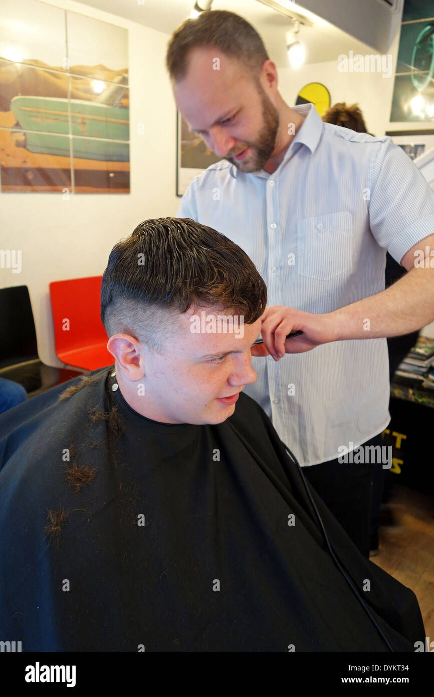 Teenage boy avoir couper les cheveux dans une boutique de barbier Banque D'Images
