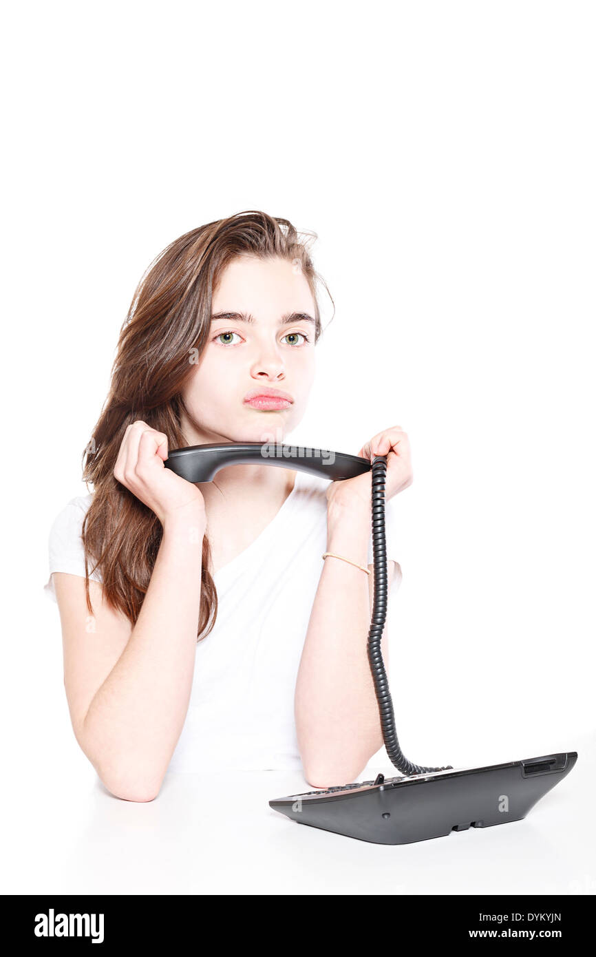 Bouder une adolescente holding récepteur du téléphone à deux mains, isolé sur blanc. Banque D'Images