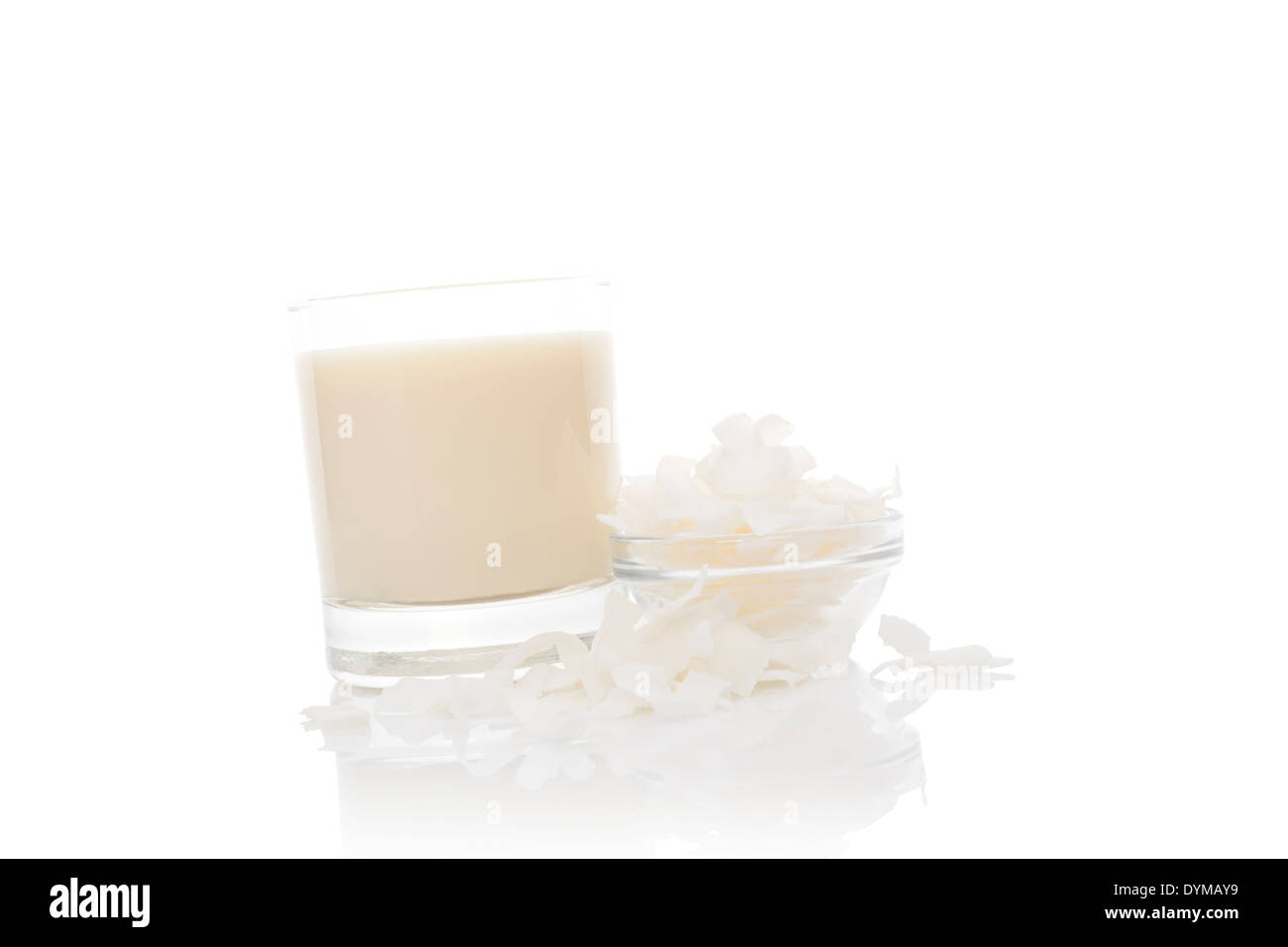 Le lait de coco dans le verre avec des flocons de noix de coco on white background, studio isolé. La cuisine asiatique culinaire ingrédient. Banque D'Images