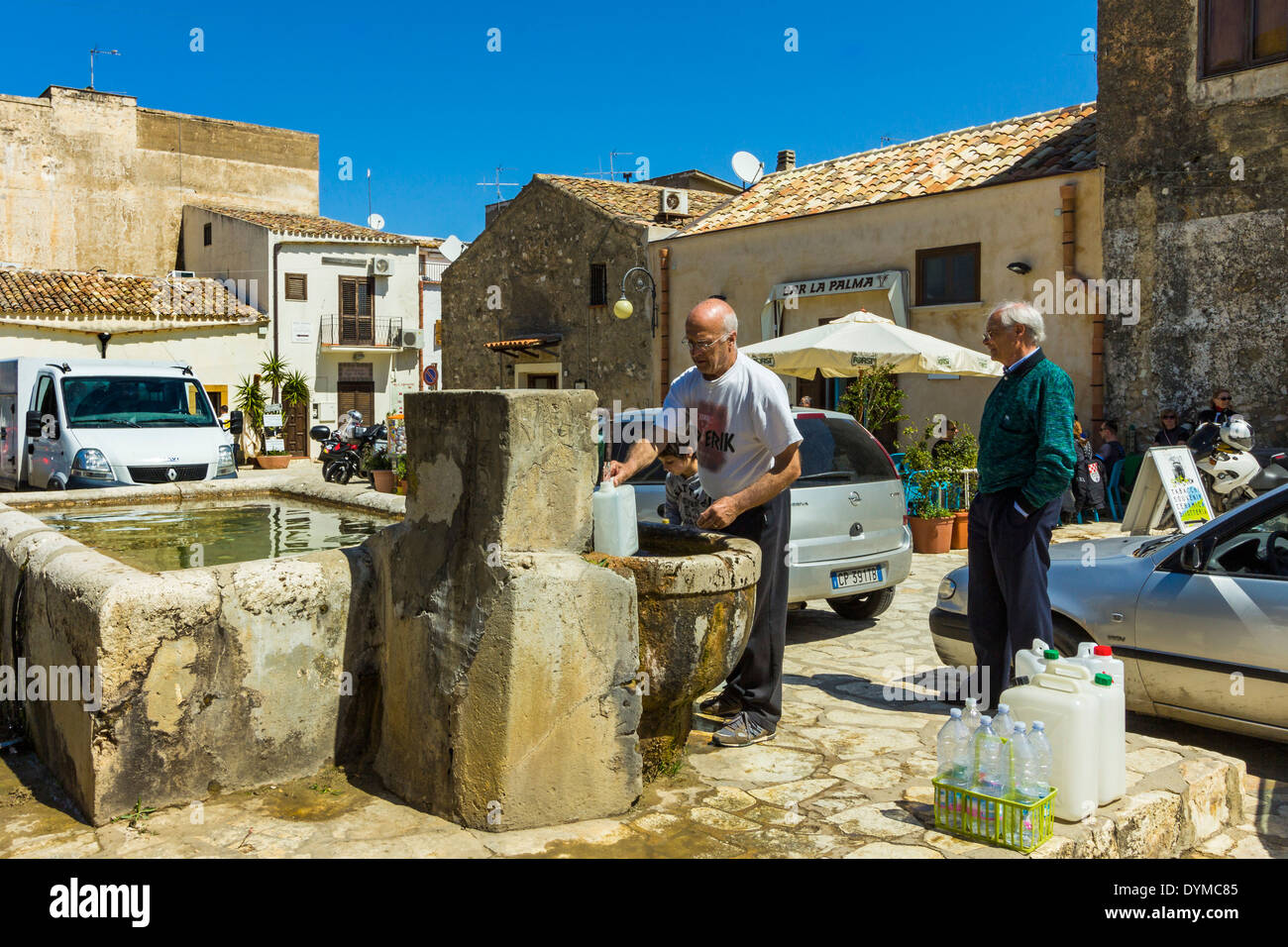 File d'attente des gens pour remplir des conteneurs au creux de l'eau dans le Baglio Isonzo à ce joli village pittoresque, Scopello, Trapani, Sicile Banque D'Images