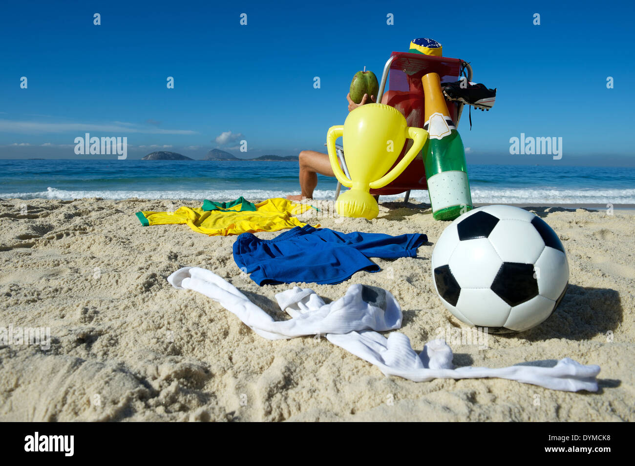 Joueur de football brésilien, Champion de célébrer en vous relaxant dans des chaises avec ballon de soccer, bouteille de champagne, et le trophée Banque D'Images