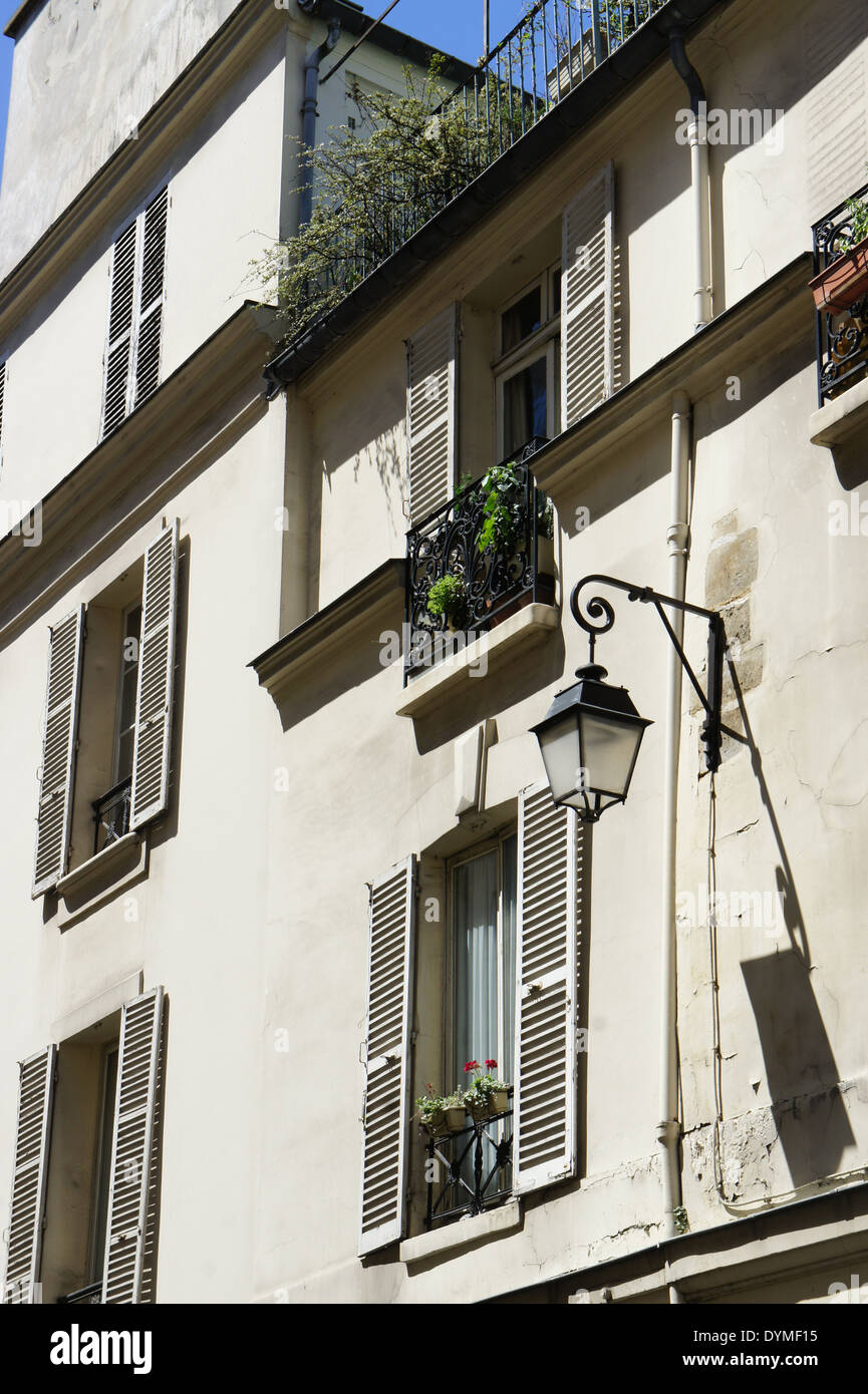 Appartement parisien blanc avec fenêtres, volets, jardinières, et d'un réverbère suspendu Banque D'Images