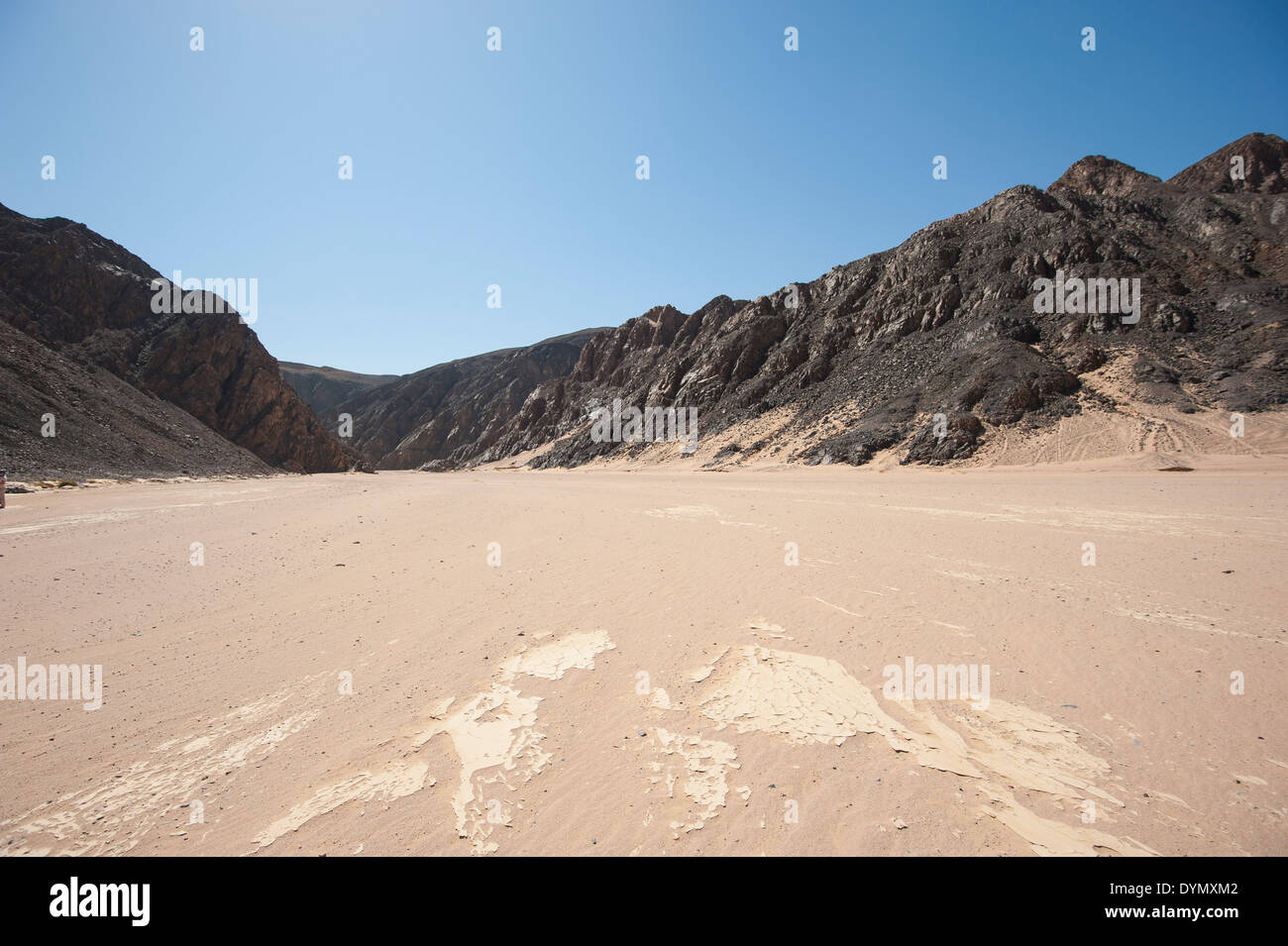 Vue vers le bas d'une vallée de la rivière Désert wadi sec dans l'aridité du climat désertique avec des montagnes Banque D'Images