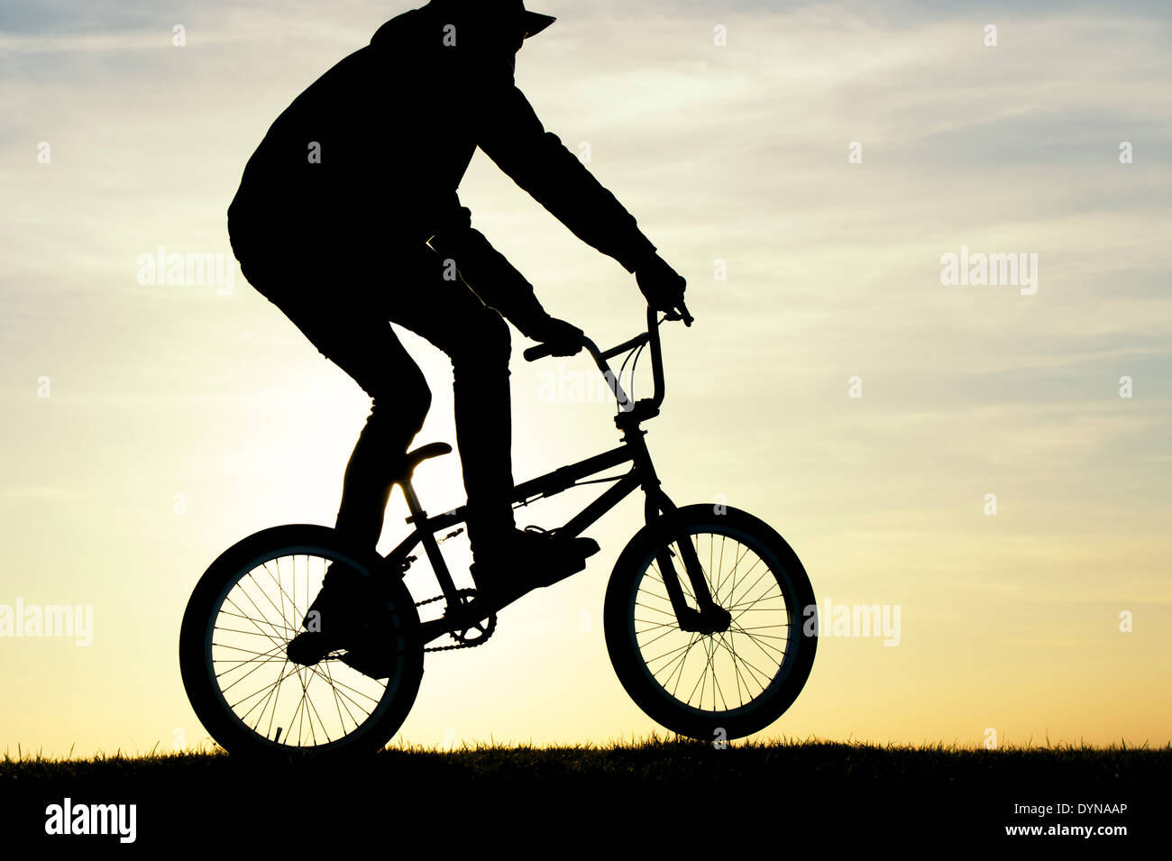 Jeune homme monté sur son vélo BMX. Silhouette Banque D'Images