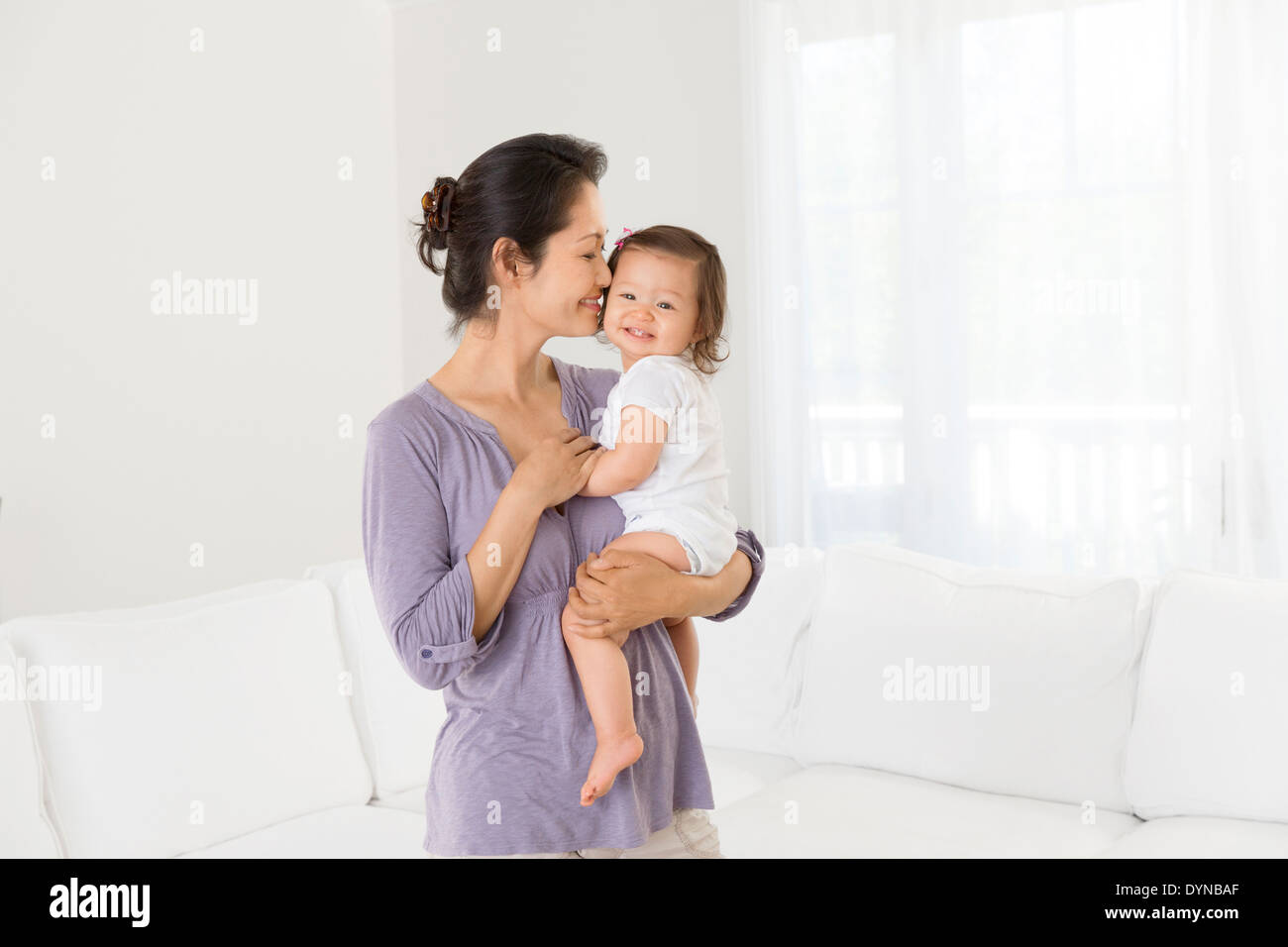 Mother holding baby girl in living room Banque D'Images