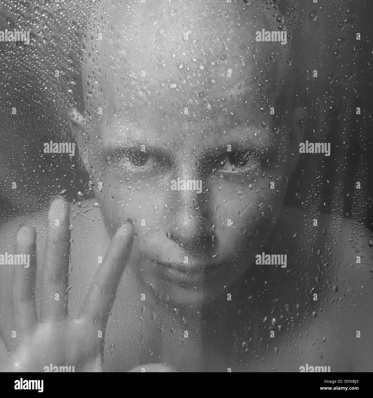 Caucasian woman peering through glass humide Banque D'Images