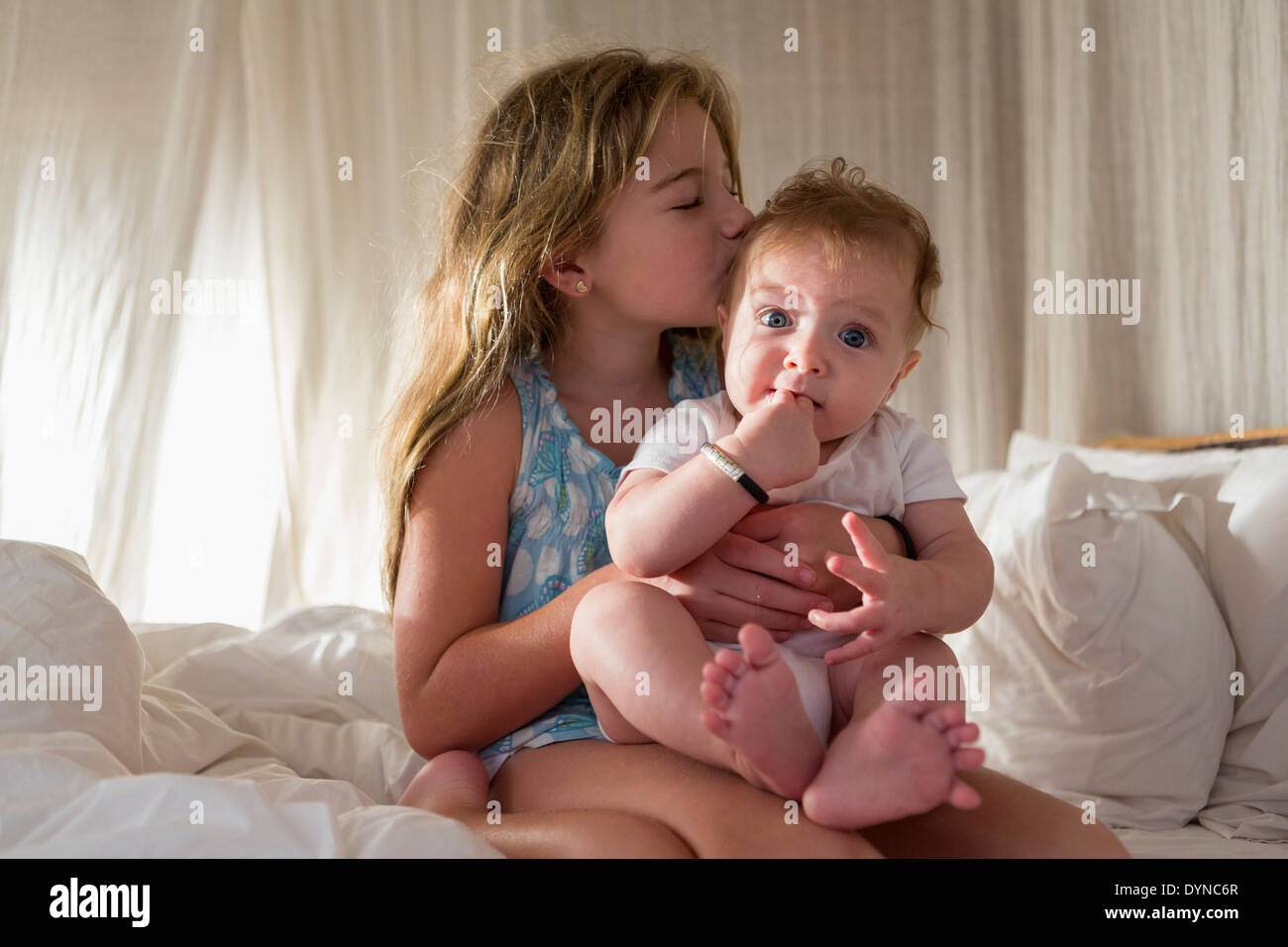 Caucasian girl kissing sœur sur canapé Banque D'Images