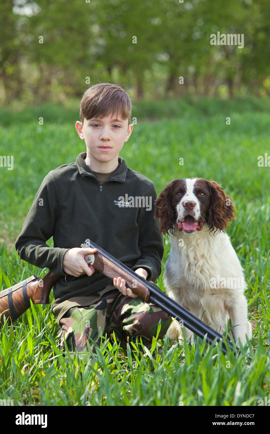 Un jeune garçon dans la campagne anglaise avec un fusil et un chien Épagneul Springer Anglais Banque D'Images