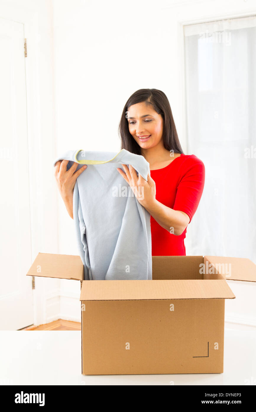 Mixed Race woman unpacking cardboard box Banque D'Images