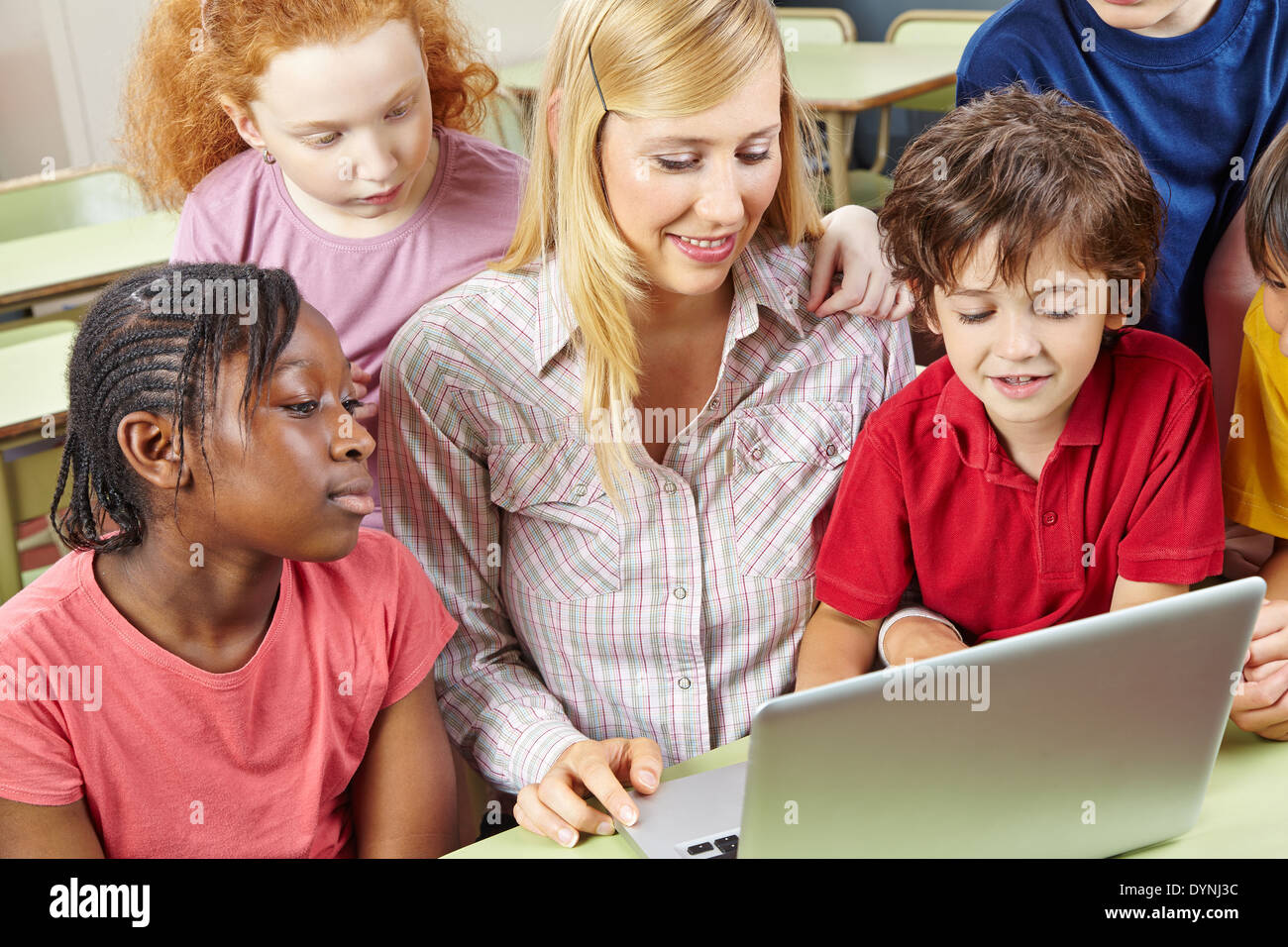 Les élèves et l'enseignant de travailler avec un ordinateur portable dans la classe de l'école élémentaire Banque D'Images