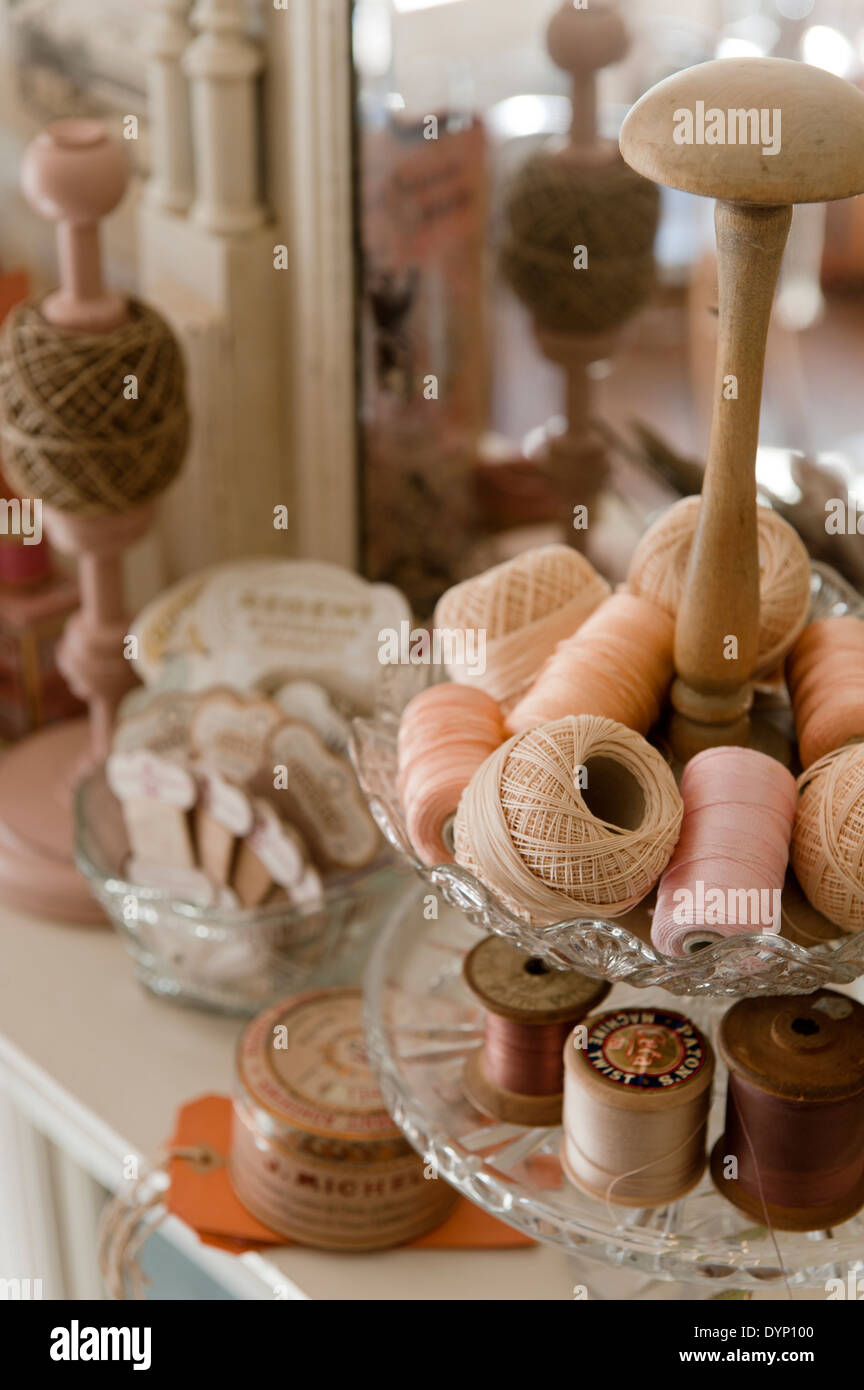 Bobines de coton Vintage dans les tons de rose et de pêche dans un stand à plusieurs niveaux Banque D'Images