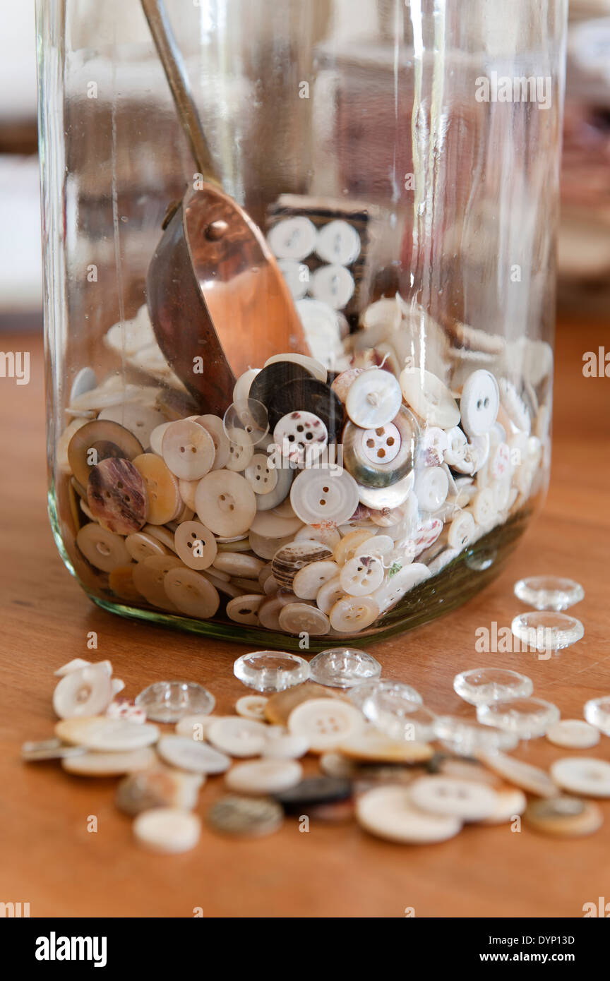 Boutons dans et autour d'un pot de verre. Banque D'Images