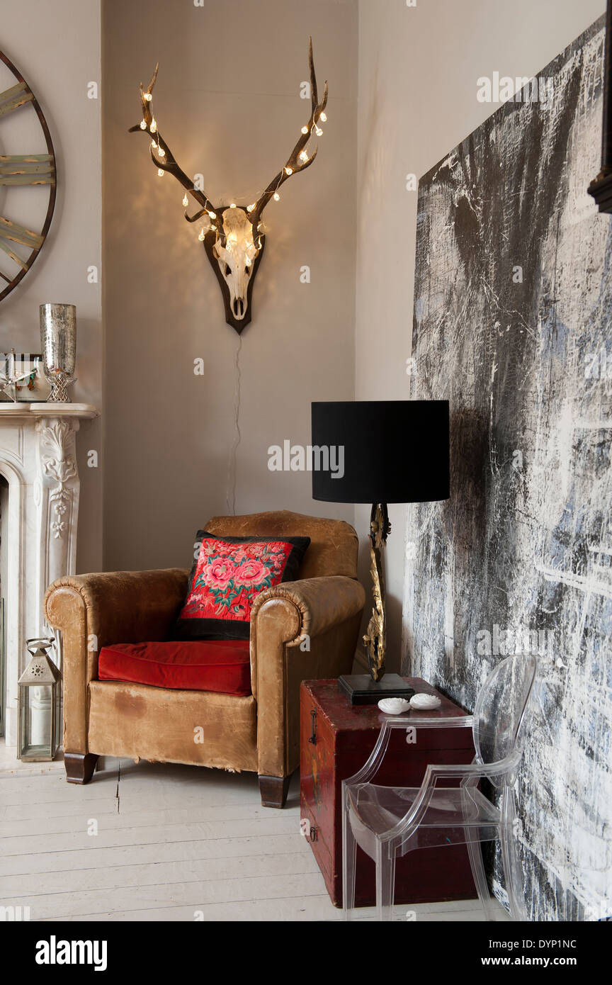 Fairy lights ornent une tête de cerf avec bois monté sur le mur au-dessus du fauteuil en cuir vintage Banque D'Images