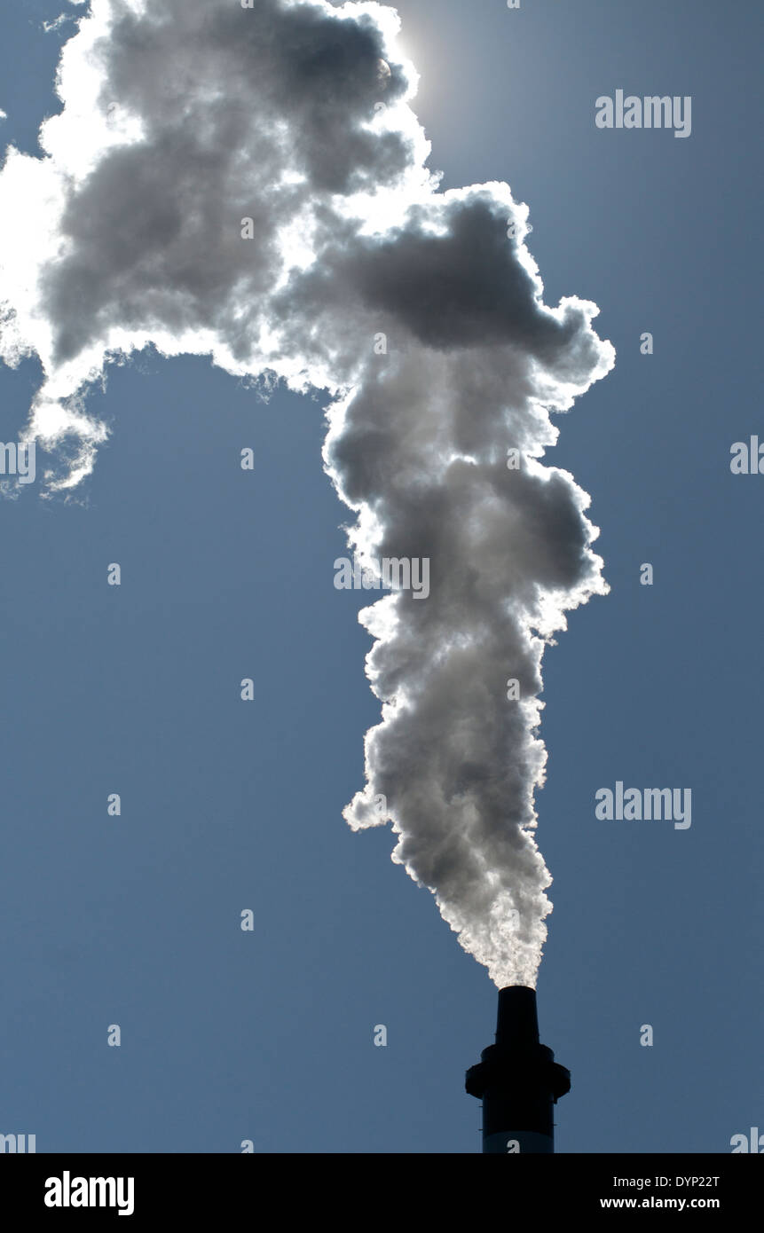 La distillerie de whisky de grain des éructations cheminée dehors la vapeur, éclairé par le soleil, ciel partiellement obscurci, contre le ciel bleu. Clyde Glasgow. Banque D'Images