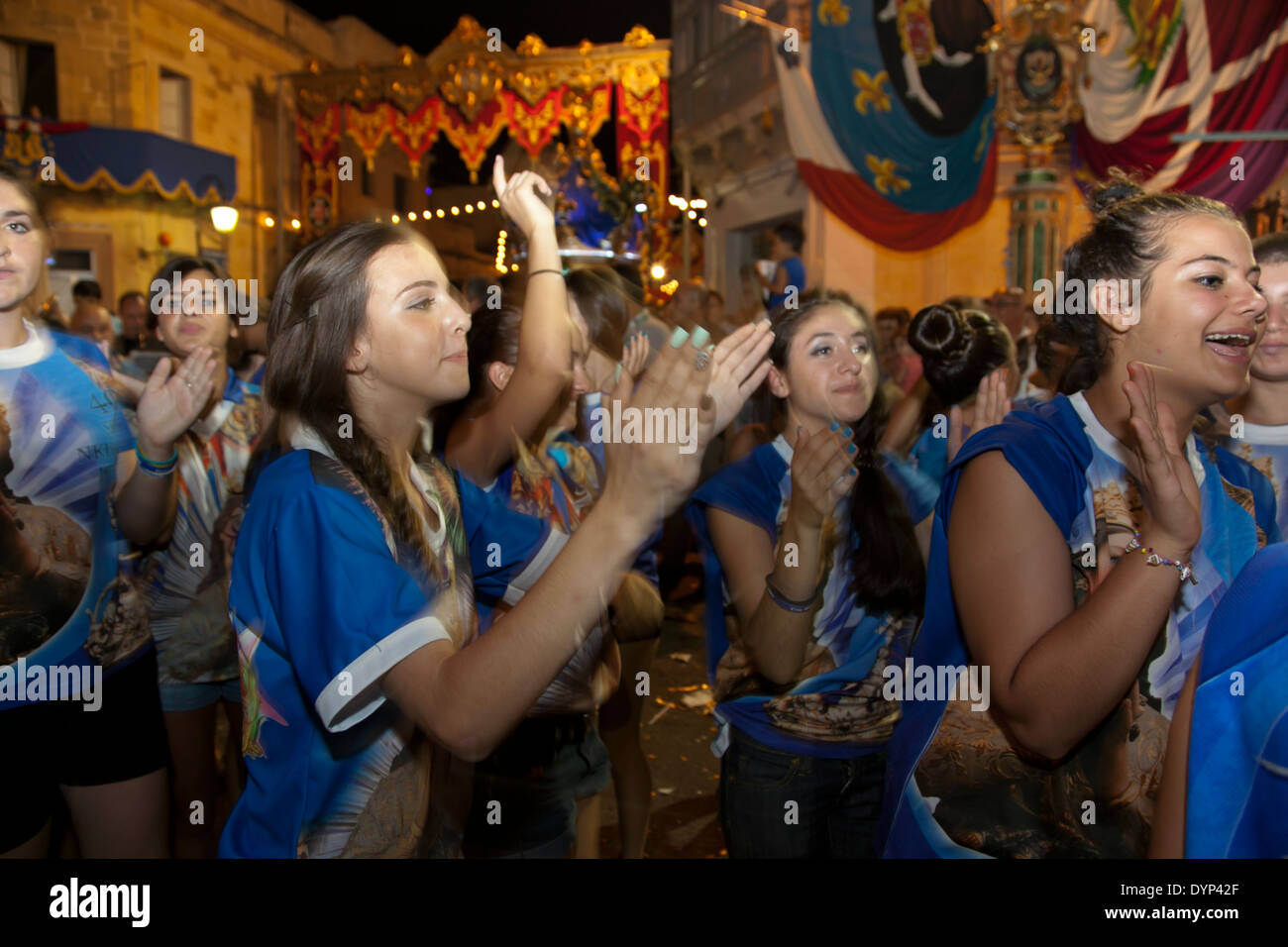 Les jeunes femmes clap et de la danse à la musique de fanfare au cours d'une ville traditionnelle fête à Malte. Banque D'Images