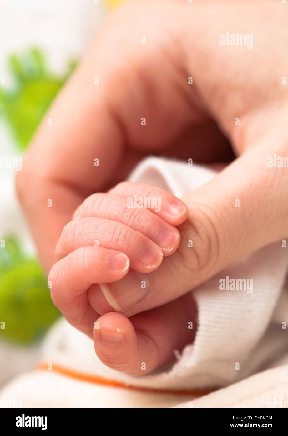 Baby holding mother's finger Banque D'Images